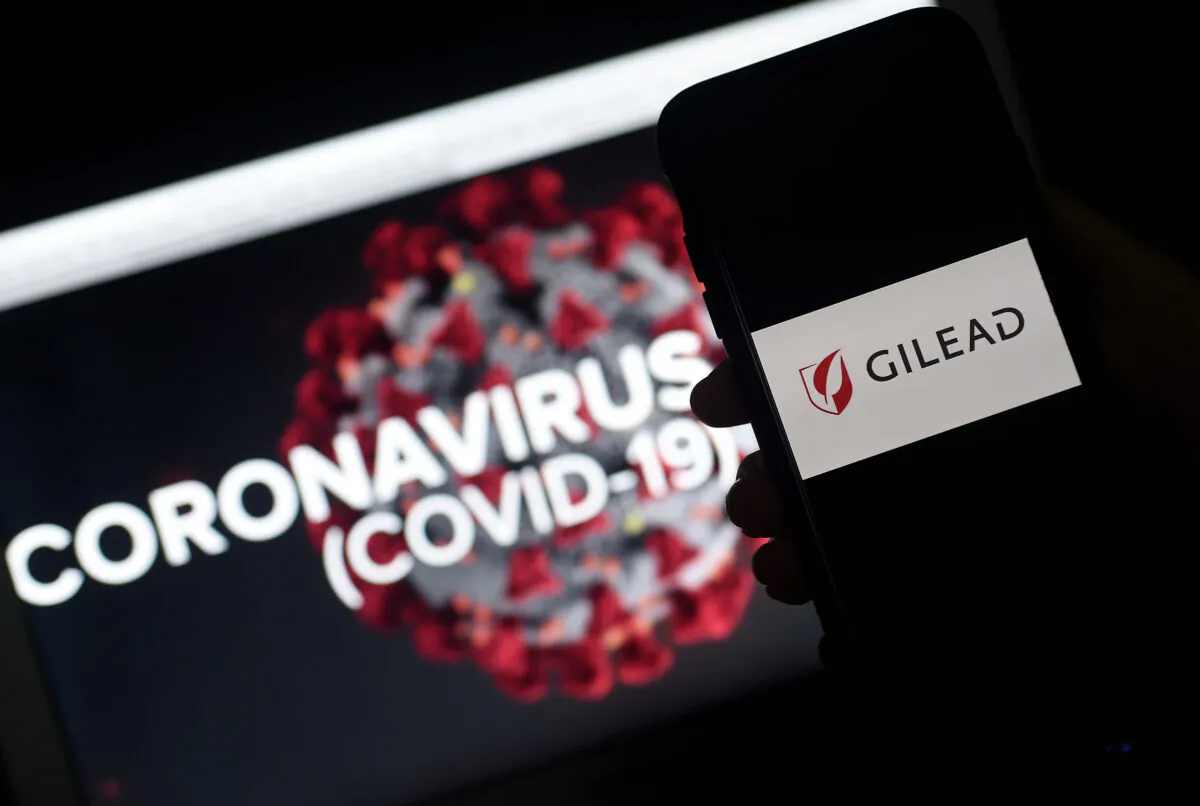 A Gilead logo is displayed on a smartphone next to a screen showing a CCP virus graphic in Arlington, Va., on March 25, 2020. (Olivier Douliery /AFP via Getty Images)
