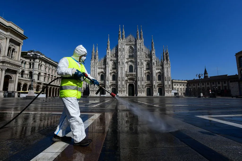 An employee wearing protective gear, working for environmental services company AMSA, sprays disinfectant on Piazza Duomo in Milan, on March 31, 2020 during the country's lockdown aimed at curbing the spread of the COVID-19 infection, caused by the novel coronavirus. (Piero Cruciatti/AFP via Getty Images)