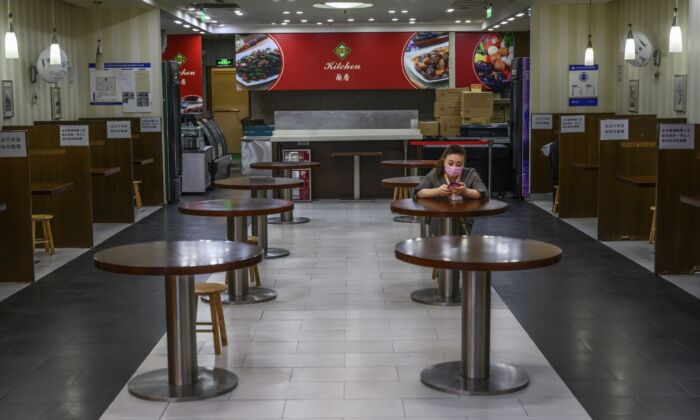 A Chinese woman waits for customers in a nearly empty restaurant at a shopping mall in Beijing, China on March 26, 2020. (Kevin Frayer/Getty Images)