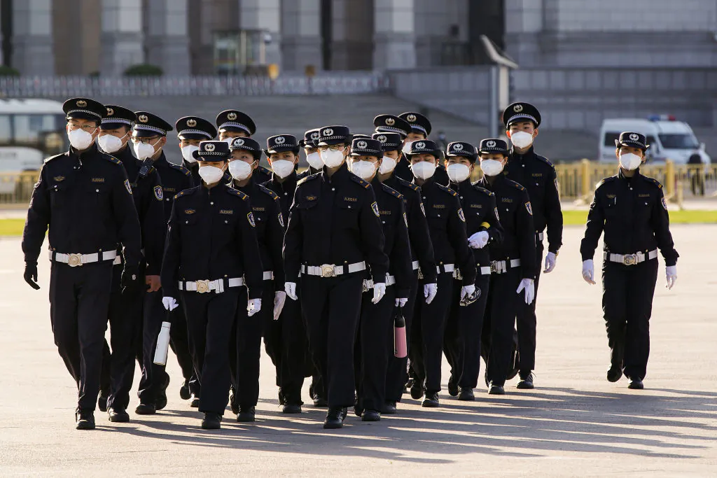 Chinese security personnel wearing protective masks march through Tiananmen Square during a national mourning of victims of COVID-19 in Beijing on April 4, 2020. (Lintao Zhang/Getty Images)