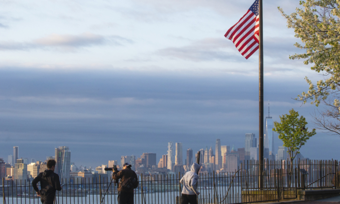 Flags are flying at half-mast as the sun rises in Manhattan on April 6, 2020, as seen from Weehawken, New Jersey. (Kena Betancur/Getty Images)