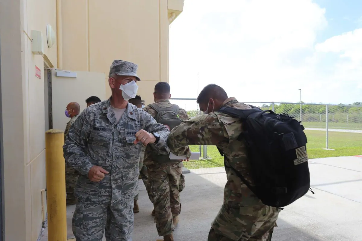Maj. Dennis Kirkland, Guam National Guard state chaplain, greets soldiers preparing to process through medical and customs checks at the GUNG readiness center after arriving on the island, on April 5, 2020. (U.S. Army National Guard photo by JoAnna Delfin)