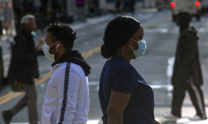 People wear masks as they walk along 34th Street in New York City on April 6, 2020. (Kena Betancur/Getty Images)