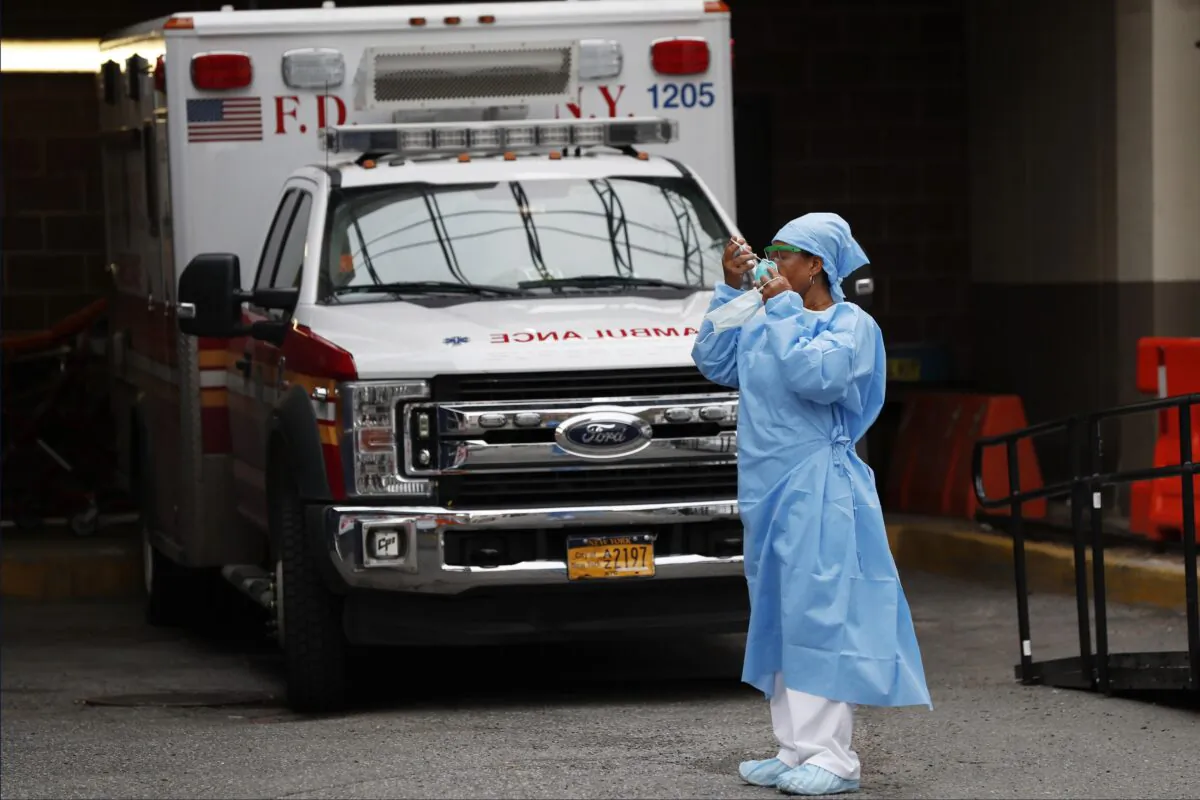 An emergency room nurse dons her face protectors after taking a break in a driveway for ambulances and emergency medical services vehicles outside Brooklyn Hospital Center's emergency room in New York, during the CCP virus crisis on April 5, 2020. (Kathy Willens/AP Photo)