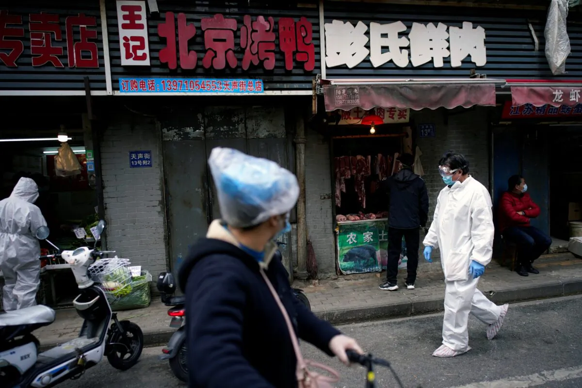 People wearing protective suits is seen at a street market in Wuhan, Hubei Province, China, on April 6, 2020. (Aly Song/Reuters)