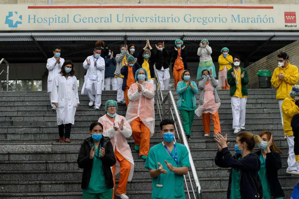 Staff members of the Gregorio Maranon Hospital applaud to pay tribute to cleaning workers in Madrid on April 1, 2020, during a national lock-down to prevent the spread of the new coronavirus. (Photo by Oscar Del Pozo/AFP/Getty Images) 