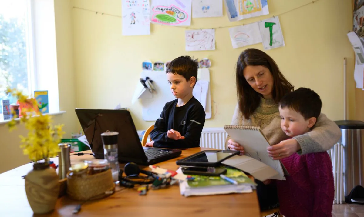Leo (C), aged 6, and Espen, aged 3, are assisted by their mother Moira as they homeschool and navigate online learning resources provided by their infant school in the village of Marsden, near Huddersfield, northern England, on March 23, 2020. (Oli Scarff/AFP via Getty Images)