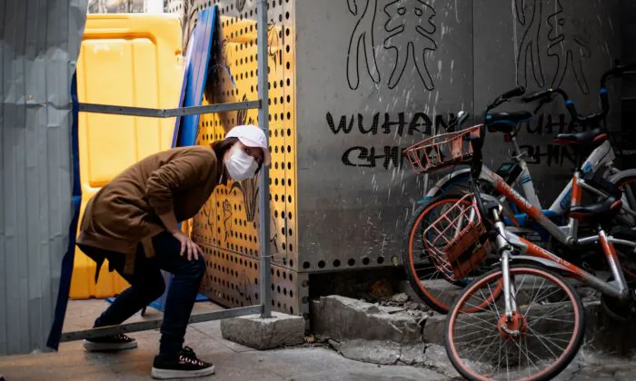 A woman wearing a face mask crosses a barricade in Wuhan China on April 7, 2020. (NOEL CELIS/AFP via Getty Images)
