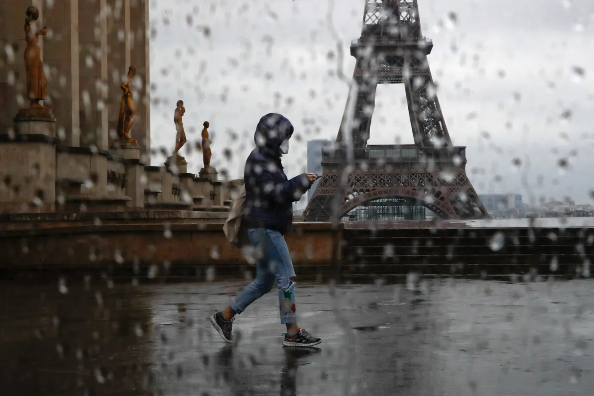 A woman with a protective face mask walks past the Eiffel tower in Paris on April 6, 2020. (Gonzalo Fuentes/Reuters)