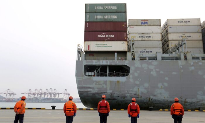 Workers watch a container ship arrive at a port in Qingdao in east China's Shandong province , China, on Feb. 4, 2020. (Chinatopix via AP)