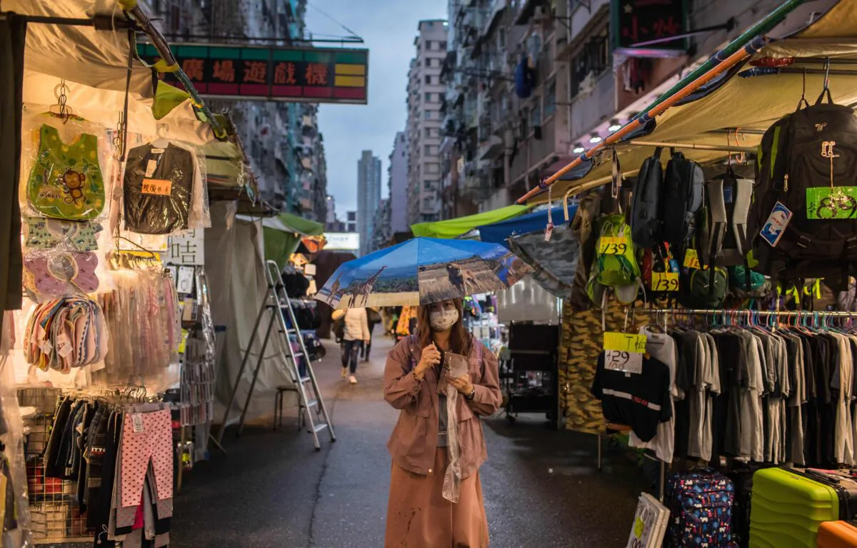 A woman wearing a face mask, amid concerns of the COVID-19 coronavirus, walks through a clothes market in Hong Kong, China, on April 5, 2020. (Dale De La Rey/AFP via Getty Images)