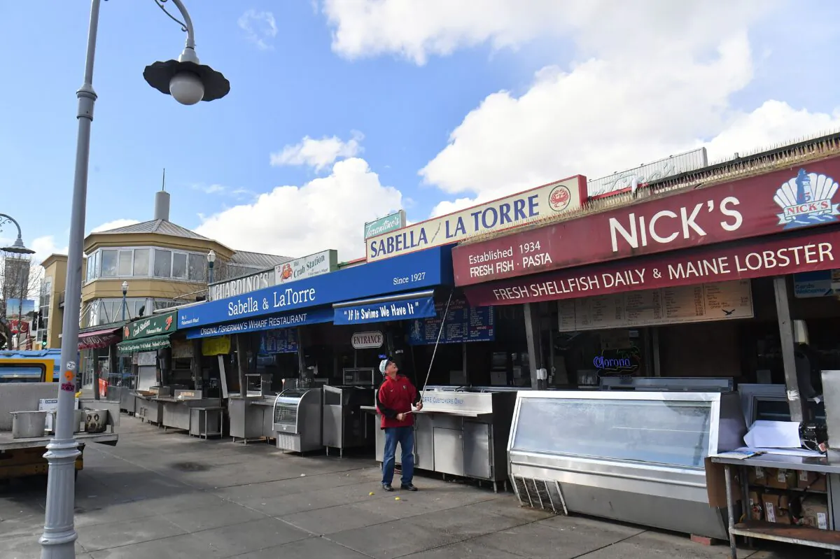 A man closes up his shop at Fisherman's Wharf in San Francisco, California on March 17, 2020. (JOSH EDELSON/AFP via Getty Images)