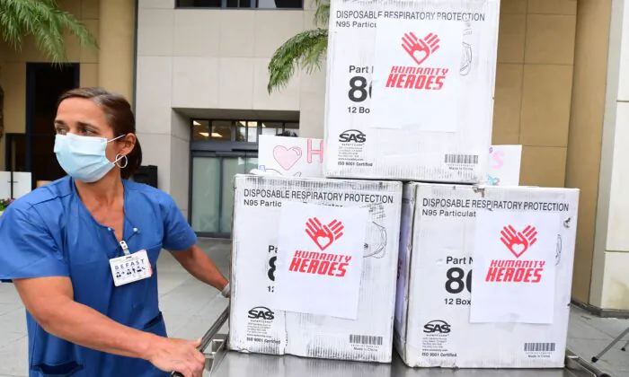 A nurse wearing a protective mask pushes a cart of masks donated by U.S. businessperson Michael "BigMike" Straumietis, to the Providence Saint Joseph Medical Center in Burbank, Calif., on April 7, 2020,(Frederic J. Brown/AFP via Getty Images)