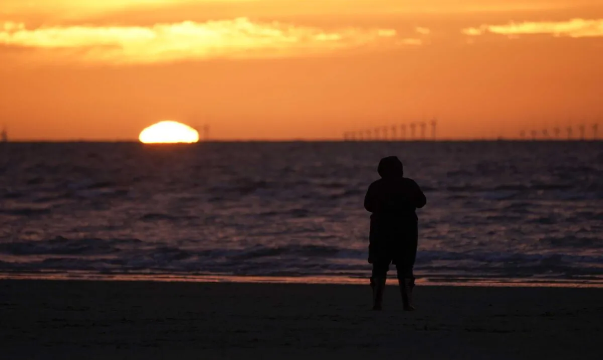 A solitary person walks on the beach at sunset in New Brighton, England, on March 19, 2020. (Christopher Furlong/Getty Images)