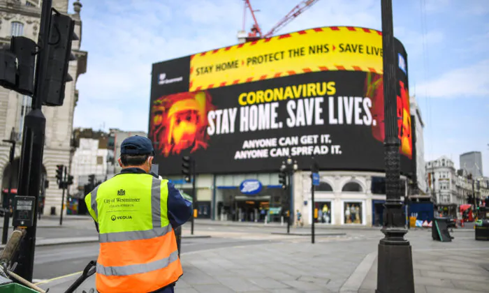 A street cleaner is seen in front of CCP virus messaging on Piccadilly Circus in London on April 8, 2020. (Peter Summers/Getty Images)