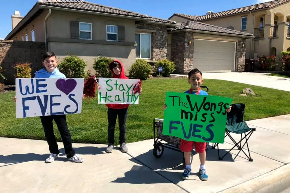 Elementary school students hold signs while watching a car parade organized by their teachers in French Valley, Calif. (Courtesy of Dawn Marie Wong)