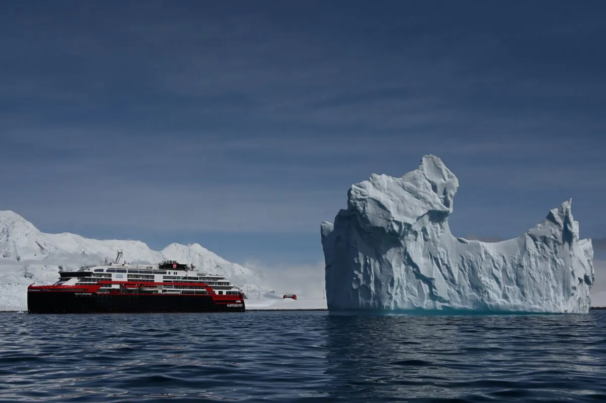 View of an iceberg and the Hurtigruten hybrid expedition cruise ship MS Roald Amundsen on Half Moon island, Antarctica on November 09, 2019. (by JOHAN ORDONEZ/Getty Images)