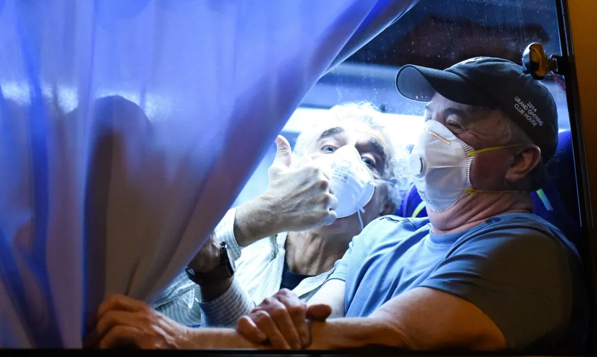 A U.S. passenger thumbs up to reporters while arriving at the Haneda Airport in Tokyo on Feb. 17, 2020, after disembarking in Yokohama from the Diamond Princess cruise ship, where people are quarantined onboard due to fears of the new COVID-19 coronavirus. (Kazuhiro Nogi/AFP via Getty Images)
