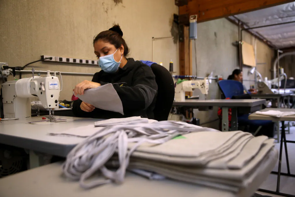 A worker at Rough Linen sews fabric masks in San Rafael, Calif., on April 6. Rough Linen, a maker of handcrafted linen bedding, has changed its production line and is now making fabric masks that are being donated to local hospitals and healthcare workers. (Photo by Justin Sullivan/Getty Images)
