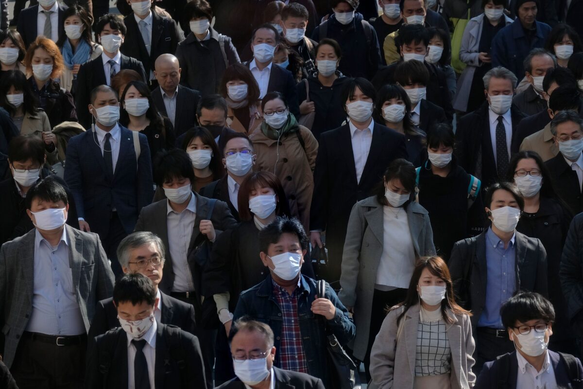 Face mask-clad commuters head to work through a street connecting from Shinjuku railway station in Tokyo on April 9, 2020. (Kazuhiro NogiI/AFP via Getty Images)