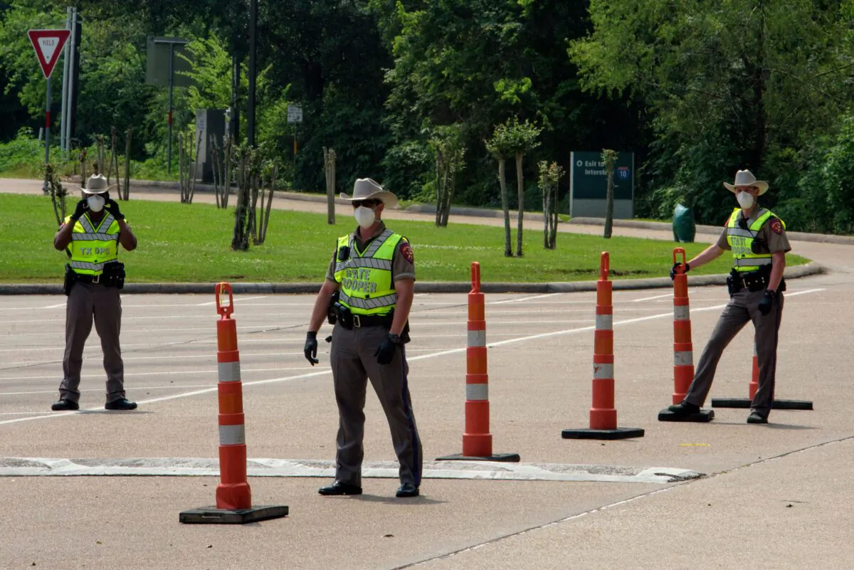 Texas State Troopers wait for drivers to arrive at a check point at the Texas Travel Information Center on the Louisiana-Texas border in Orange, Texas on April 7, 2020. (Mark Felix/AFP via Getty Images)
