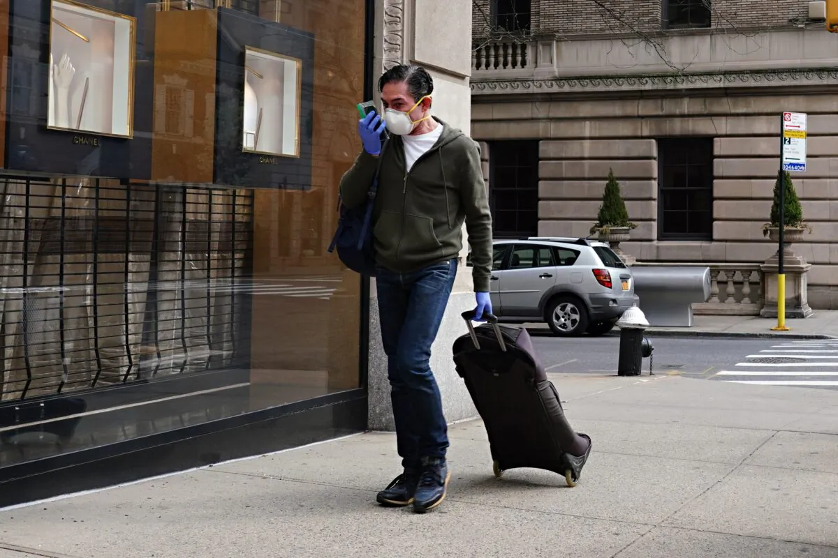 A man wearing a protective mask and gloves talks on a cell phone in a ziplock bag during the COVID-19 pandemic in New York City on April 8, 2020. (Cindy Ord/Getty Images)