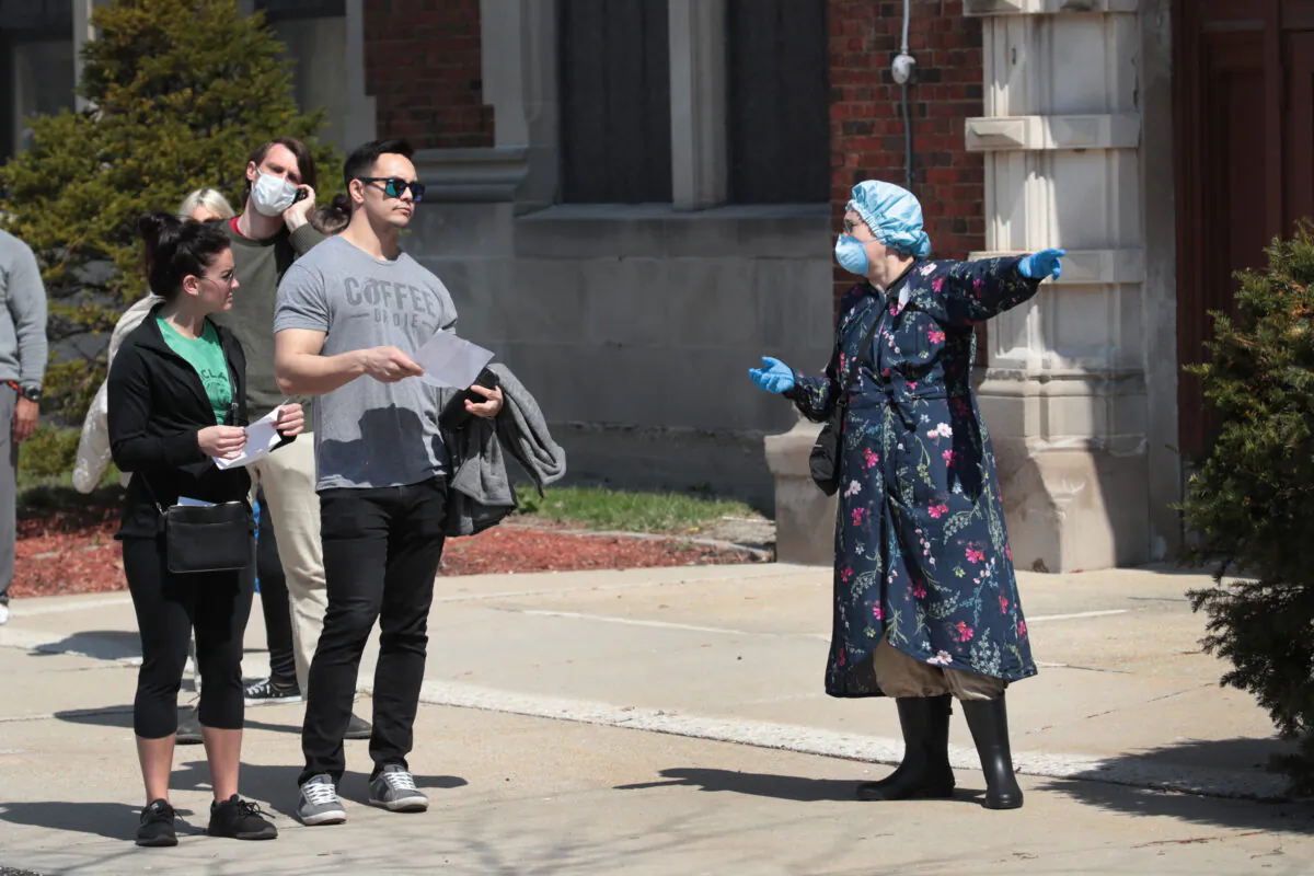 A poll worker helps voters at a polling place at Riverside University High School in Milwaukee, Wisconsin on April 7, 2020. (Scott Olson/Getty Images)