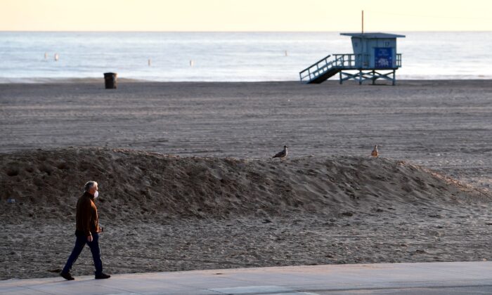 A man wears a mask while walking on a quiet afternoon at Santa Monica Beach, Calif., on April 10, 2020. (Frederic J. Brown/AFP via Getty Images)