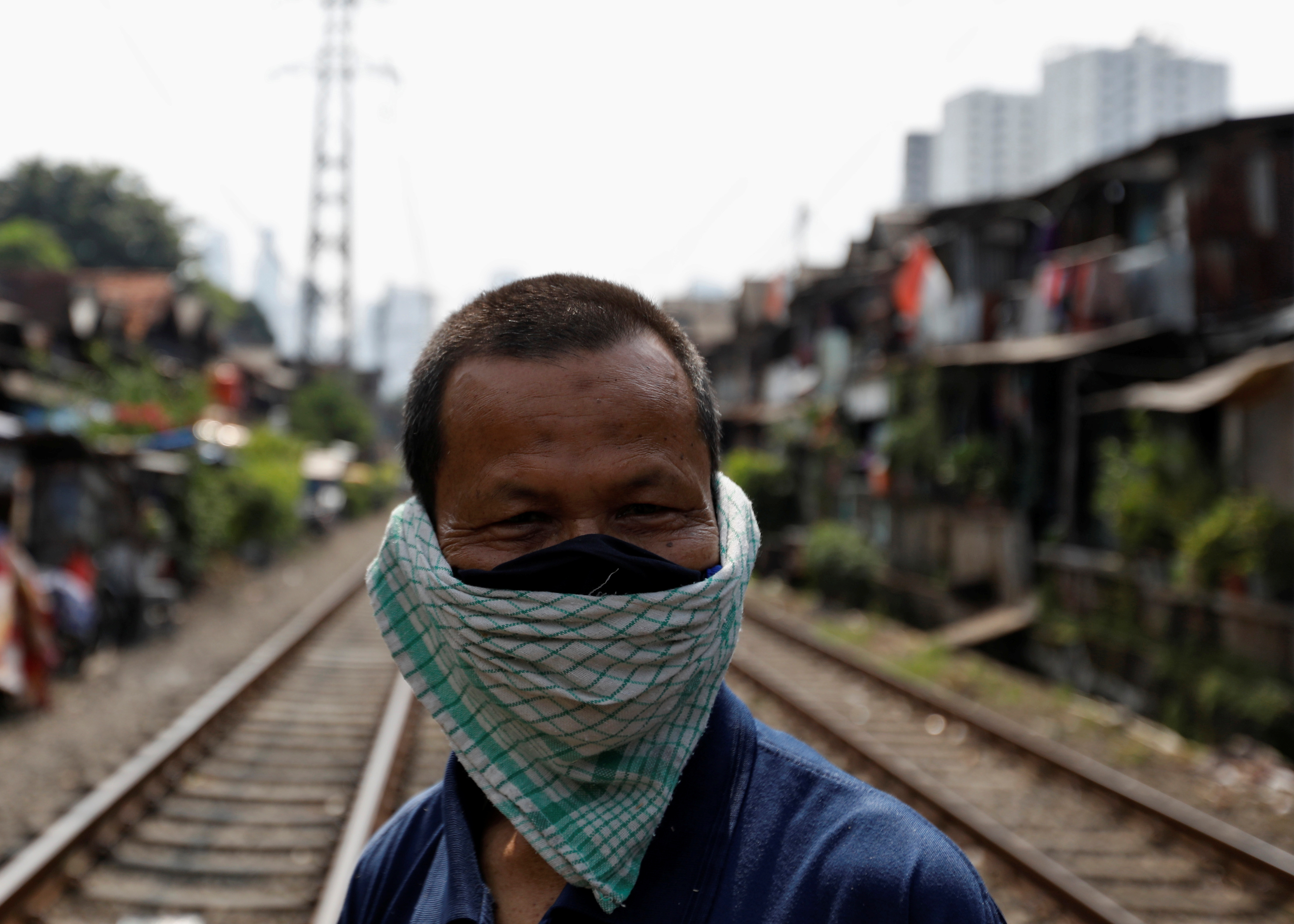 A man covers his face with a napkin along rail tracks, during the large-scale social restrictions to prevent the spread of the CCP virus in Jakarta, Indonesia, on April 12, 2020.