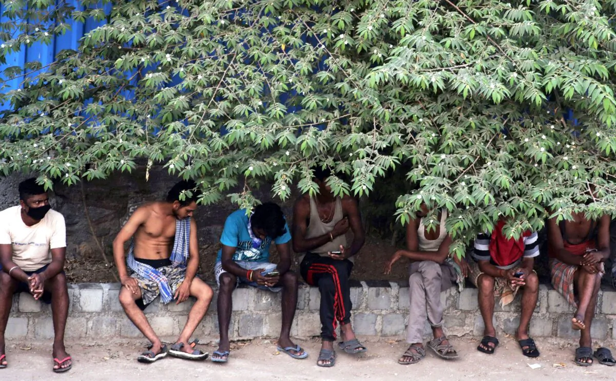 Migrant workers sit in the shade outside a slum area in Mumbai, India, on April 11, 2020. Social distancing has become the law in India, but in poor countries, observing social distancing is an option for only the better off. (AP Photo/Rajanish Kakade)