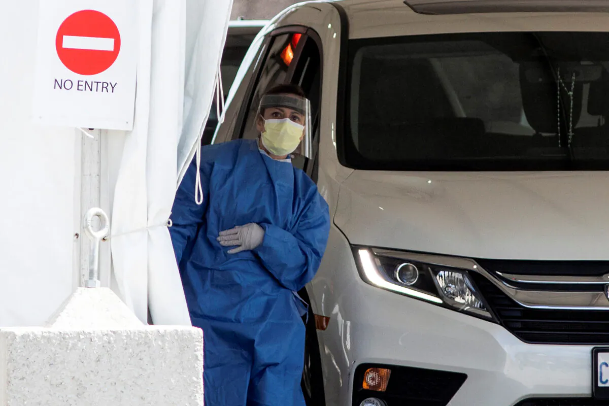 A frontline healthcare worker attends people at the Etobicoke General Hospital drive-thru COVID-19 assessment centre, in Toronto on April 9, 2020. (Carlos Osorio/Reuters)