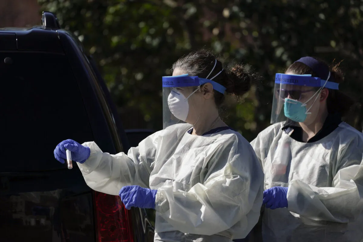 A medical professional from Children's National Hospital carries a CCP virus test specimen after administering a test at a drive-through testing site for children age 22 and under at Trinity University in Washington on April 2, 2020. (Drew Angerer/Getty Images)