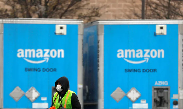A worker in a face mask walks by trucks parked at an Amazon facility as the global CCP virus (COVID-19) outbreak continued in Bethpage on Long Island in New York, on March 17, 2020. (Andrew Kelly/File Photo/Reuters)