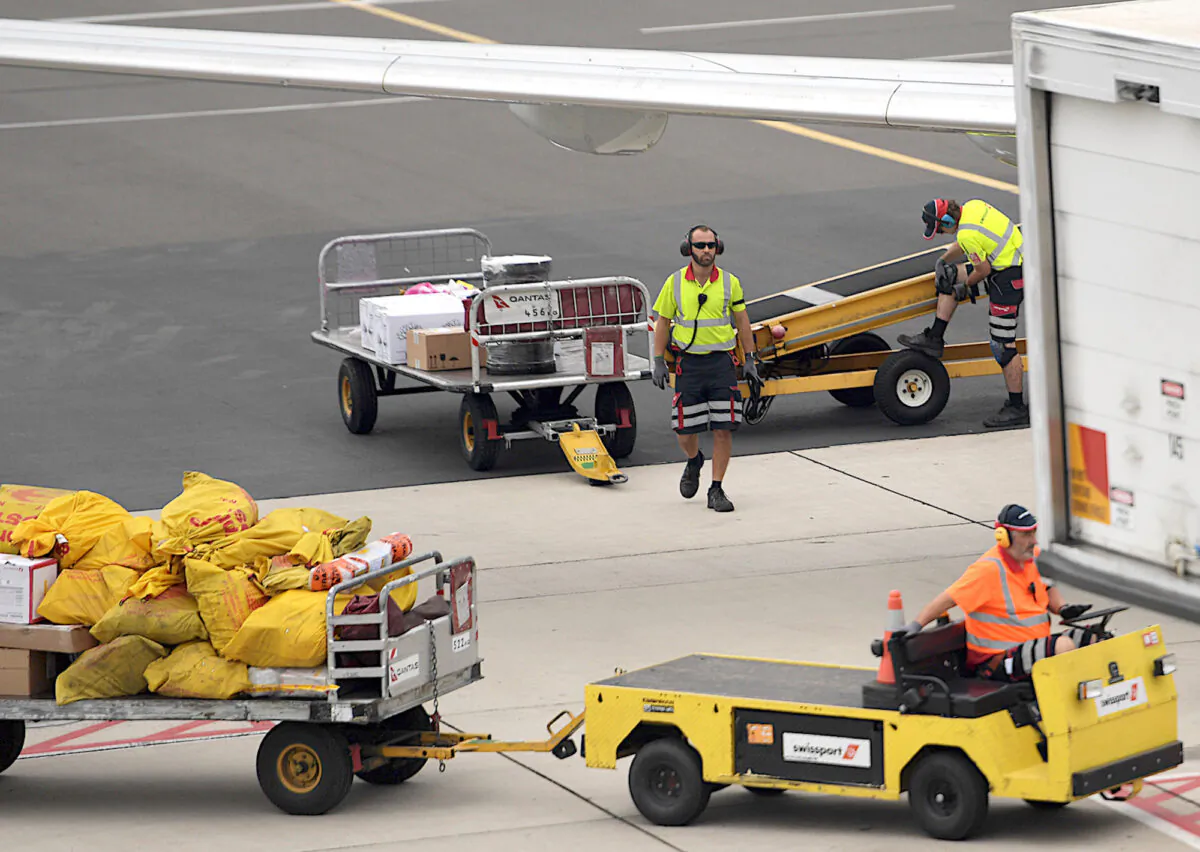 Baggage handers load a Qantas plane at Adelaide Airport in South Australia on April 1, 2020. (Tracey Nearmy/Getty Images)