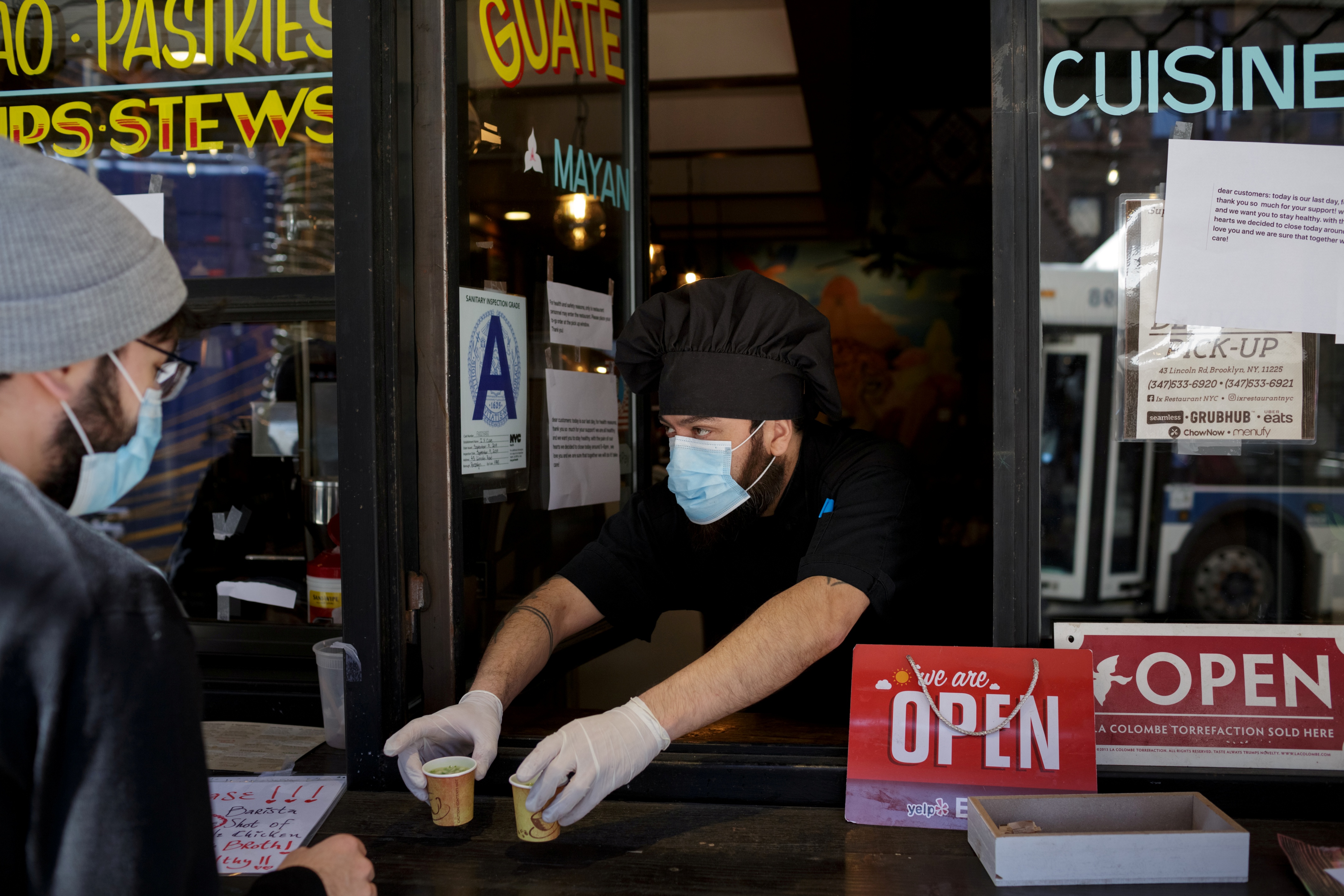 Chef and part-owner Jorge Cardenas, 41, hands customers free shots of broth while they wait for their takeout order outside of Ix restaurant in the Brooklyn borough of New York City, U.S., on April 2, 2020 amid the CCP virus outbreak. (Anna Watts/Reuters)