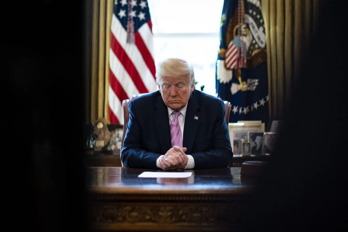 President Donald Trump bows his head during a Easter blessing by Bishop Harry Jackson, senior pastor at Hope Christian Church in Beltsville, Md., in the Oval Office of the White House in Washington, on  April 10, 2020. (Al Drago/ Pool/Getty Images)