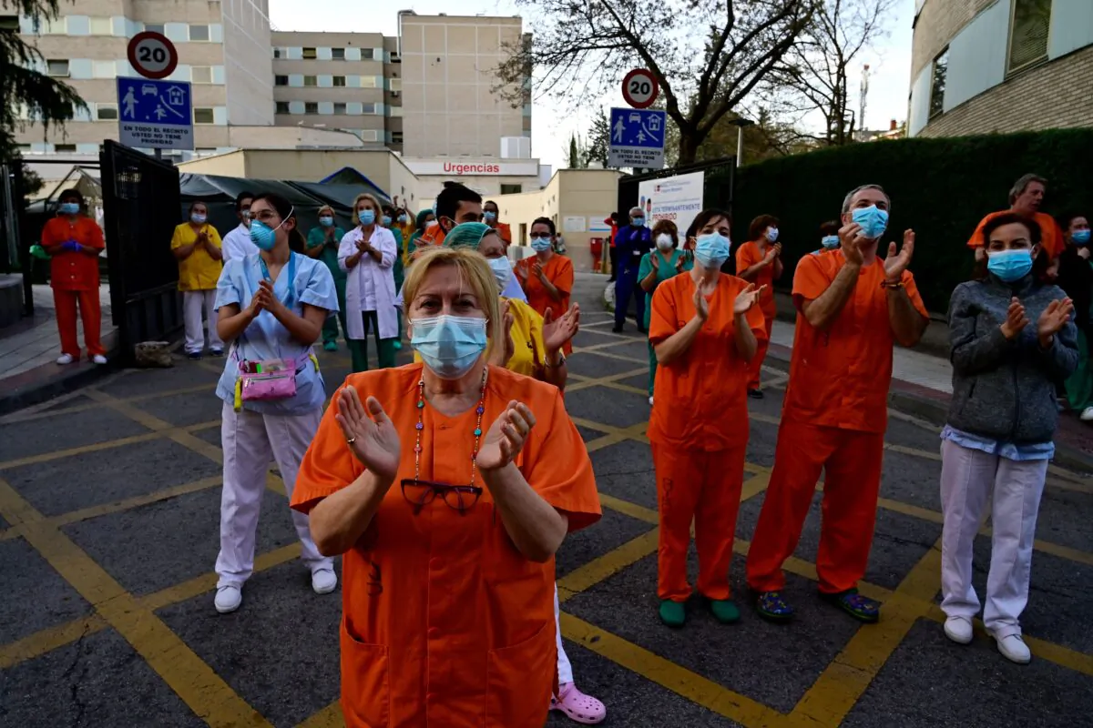 During a national lockdown to prevent the spread of the CCP virus, healthcare workers applaud in return as they are cheered on outside the Gregorio Maranon Hospital in Madrid on April 12, 2020. (Pierre-Philippe Marcou /AFP via Getty Images)