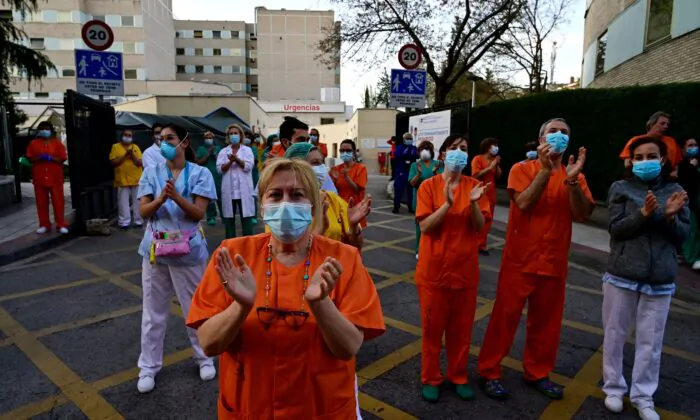 During a national lockdown to prevent the spread of the CCP virus,  healthcare workers applaud in return as they are cheered on outside the Gregorio Maranon Hospital in Madrid on April 12, 2020. (Pierre-Philippe Marcou /AFP via Getty Images)