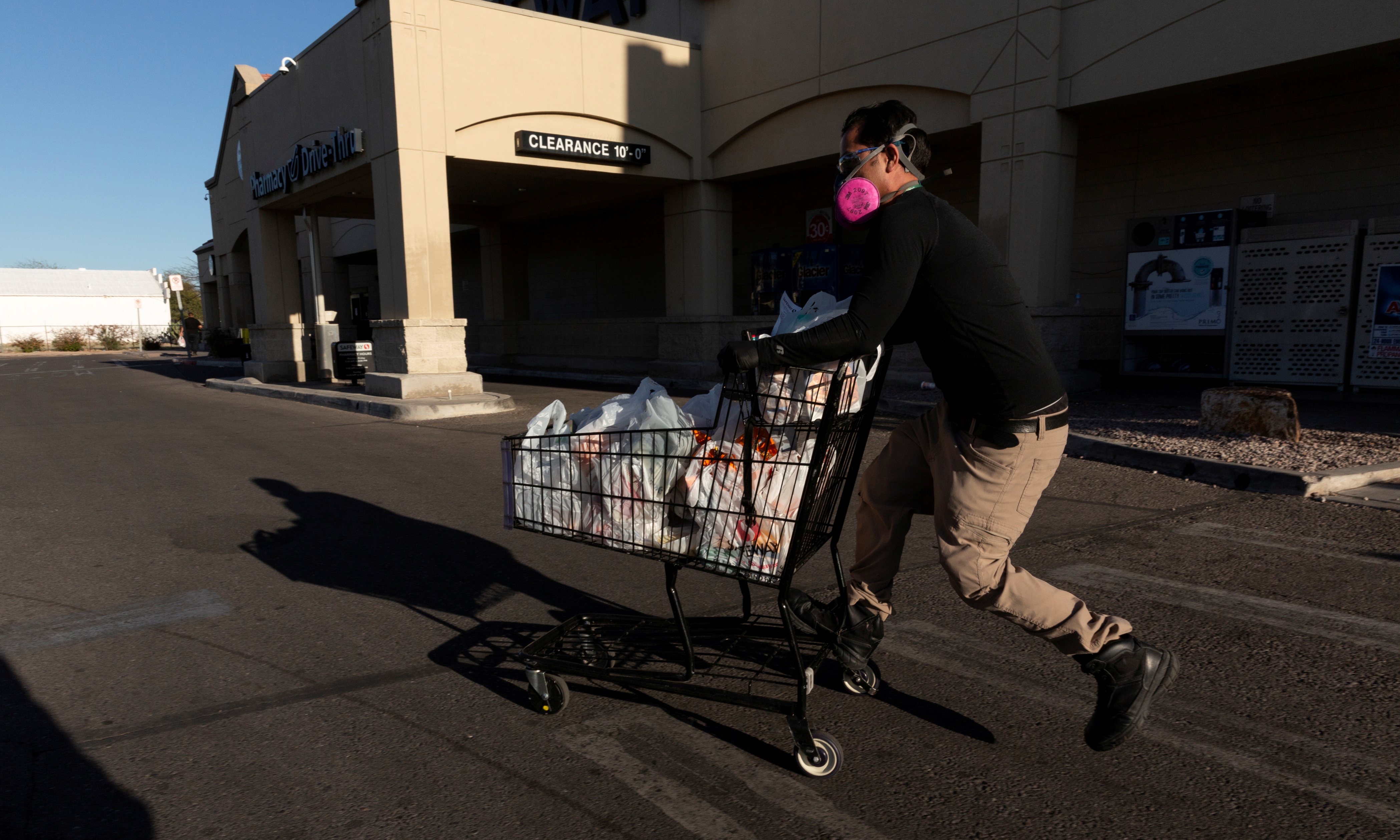 Instacart employee Eric Cohn, 34, heads to his car outside a Safeway grocery store while wearing a respirator mask
