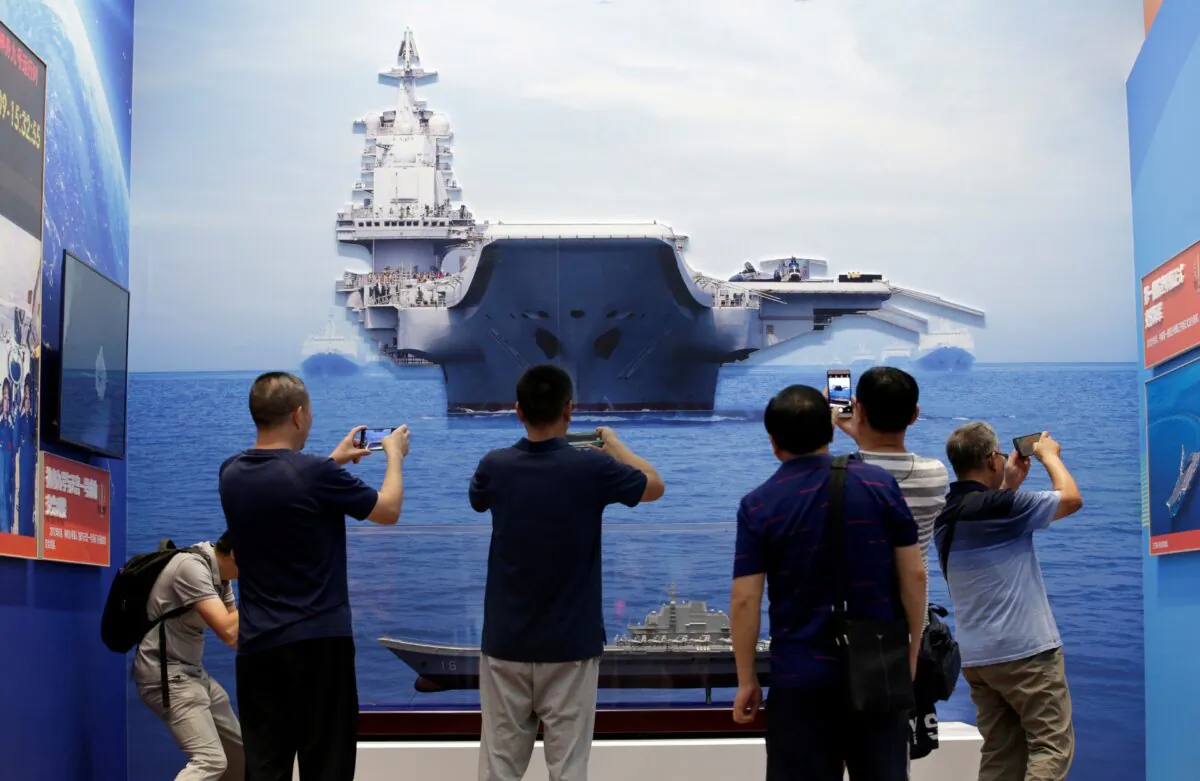 Visitors hold their mobile phones in front of exhibits showing People's Liberation Army (PLA) Navy's first aircraft carrier Liaoning at the Beijing Exhibition Center, in Beijing, China, on Sept. 24, 2019. (Jason Lee/File Photo/Reuters)