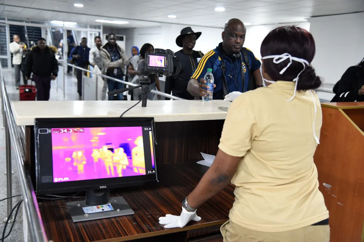 A Port Health Service staff member stands next to a thermal scanner as passengers arrive at the Murtala Mohammed International Airport in Lagos, Nigeria, on January 27, 2019. (PIUS UTOMI EKPEI/AFP via Getty Images)