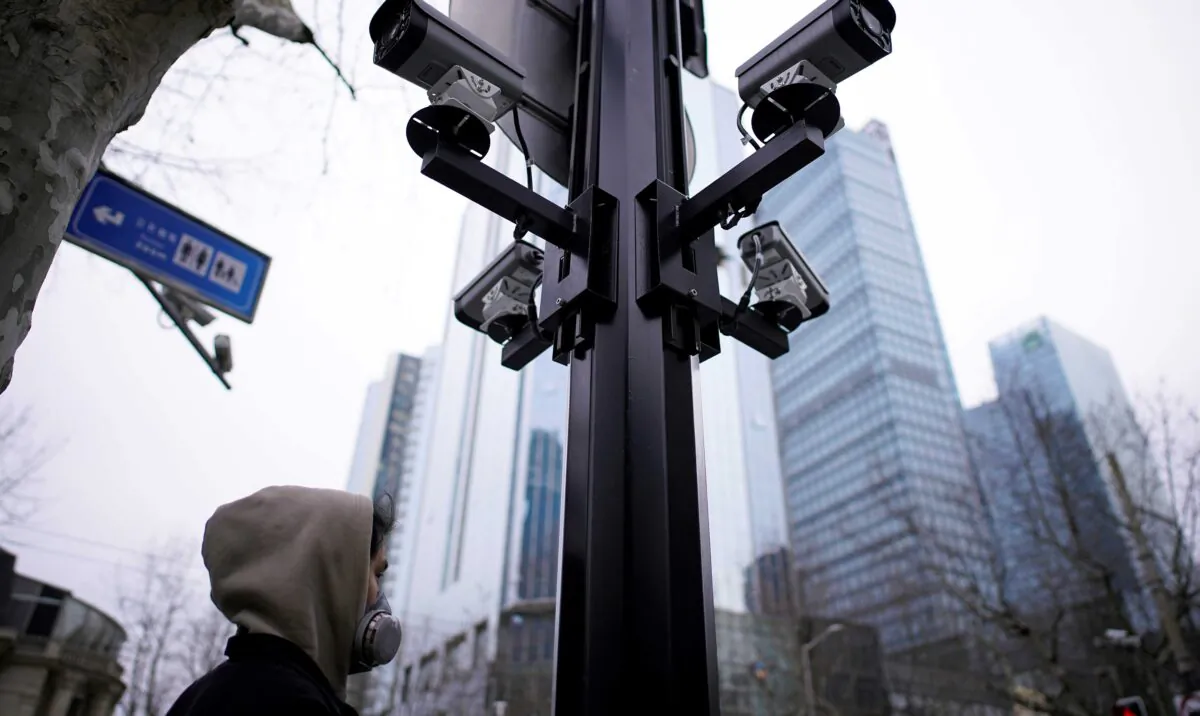 A man wearing a protective face mask walks under surveillance cameras as China is hit by an outbreak of the novel coronavirus, in Shanghai, on March 4, 2020. (Aly Song/Reuters)