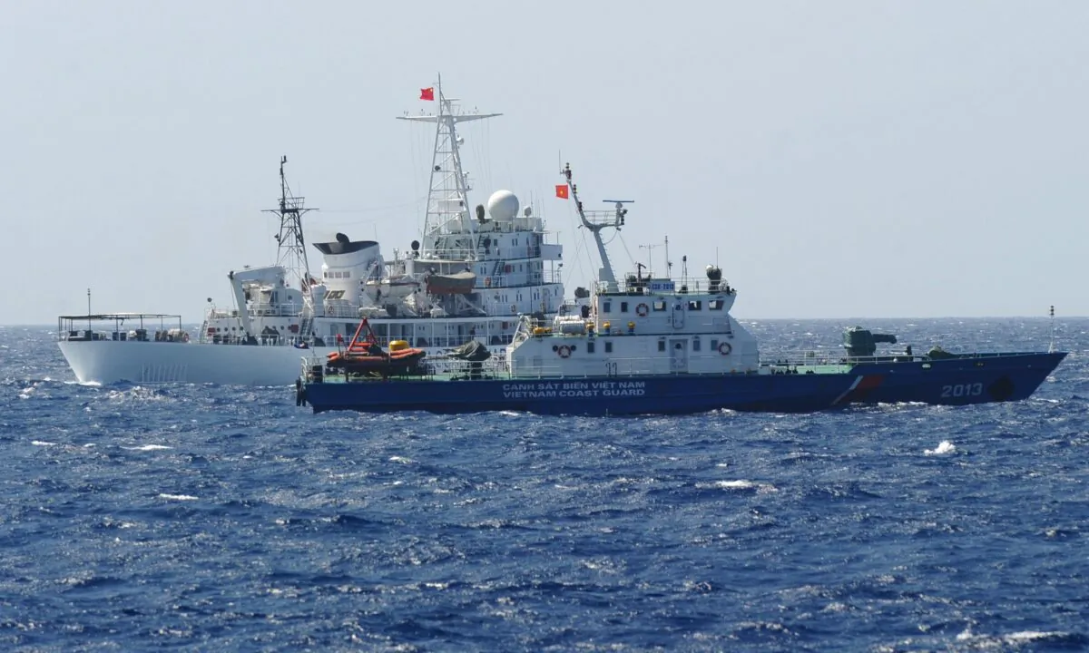 A Chinese coast guard ship (back) sails next to a Vietnamese coast guard vessel (front) near China's oil drilling rig in disputed waters in the South China Sea on May 14, 2014. (Hoang Dinh Nam/AFP via Getty Images）