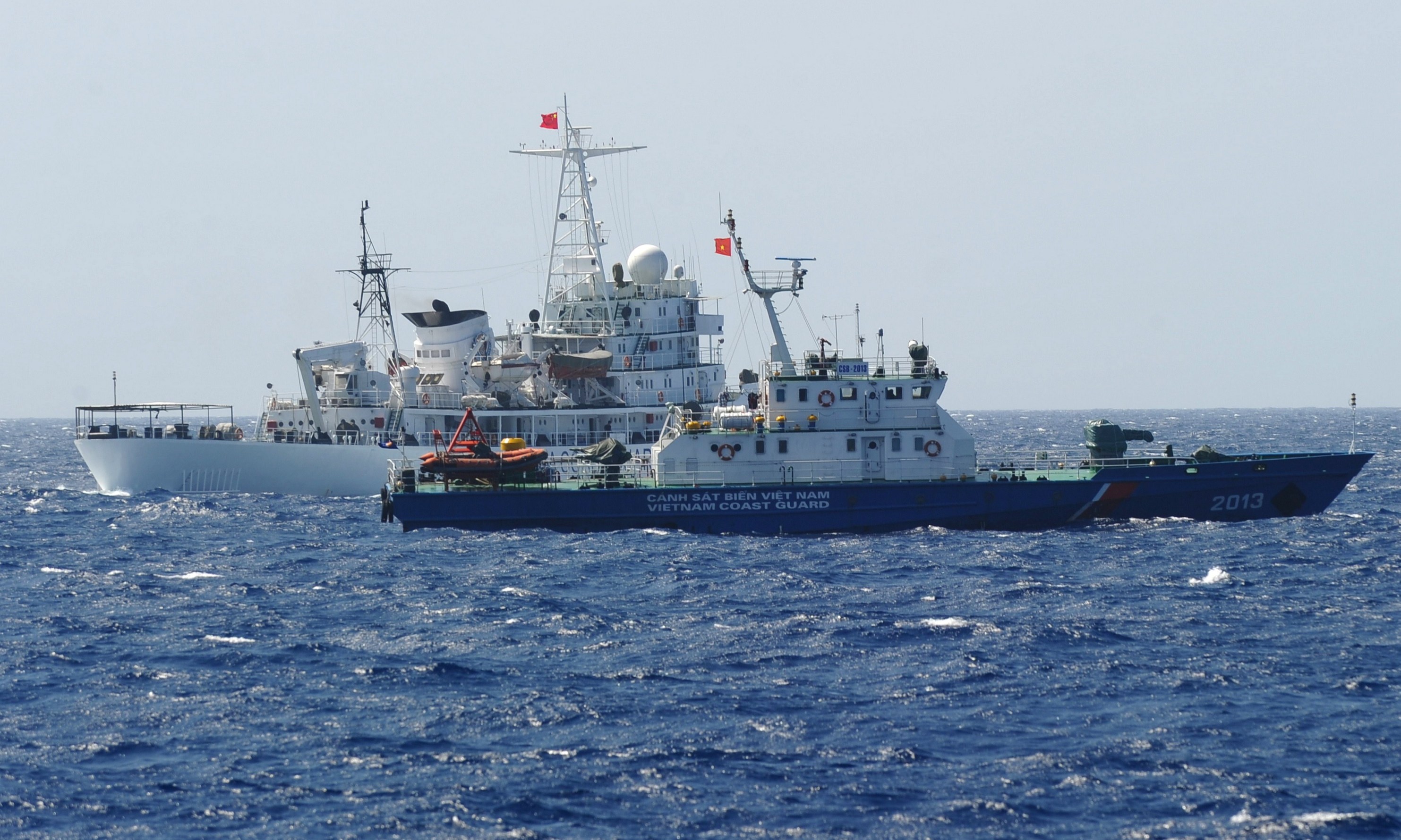 A Chinese coast guard ship (back) sailing next to a Vietnamese coast guard vessel (front) near China's oil drilling rig in disputed waters in the South China Sea on May 14, 2014。(HOANG DINH NAM/AFP via Getty Images)