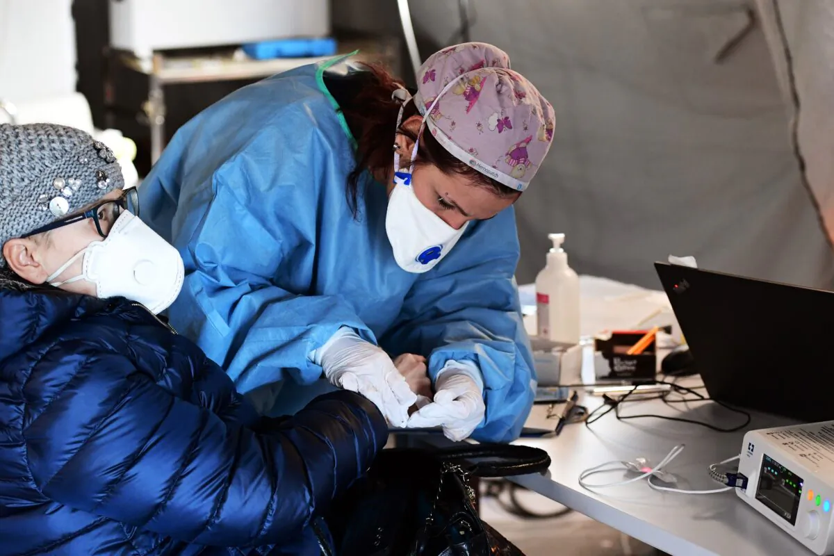 A elderly woman receives assistance in the a pre-triage medical tent in front of the Cremona hospital in Cremona, northern Italy, on March 4, 2020. (Miguel Medina/AFP via Getty Images)