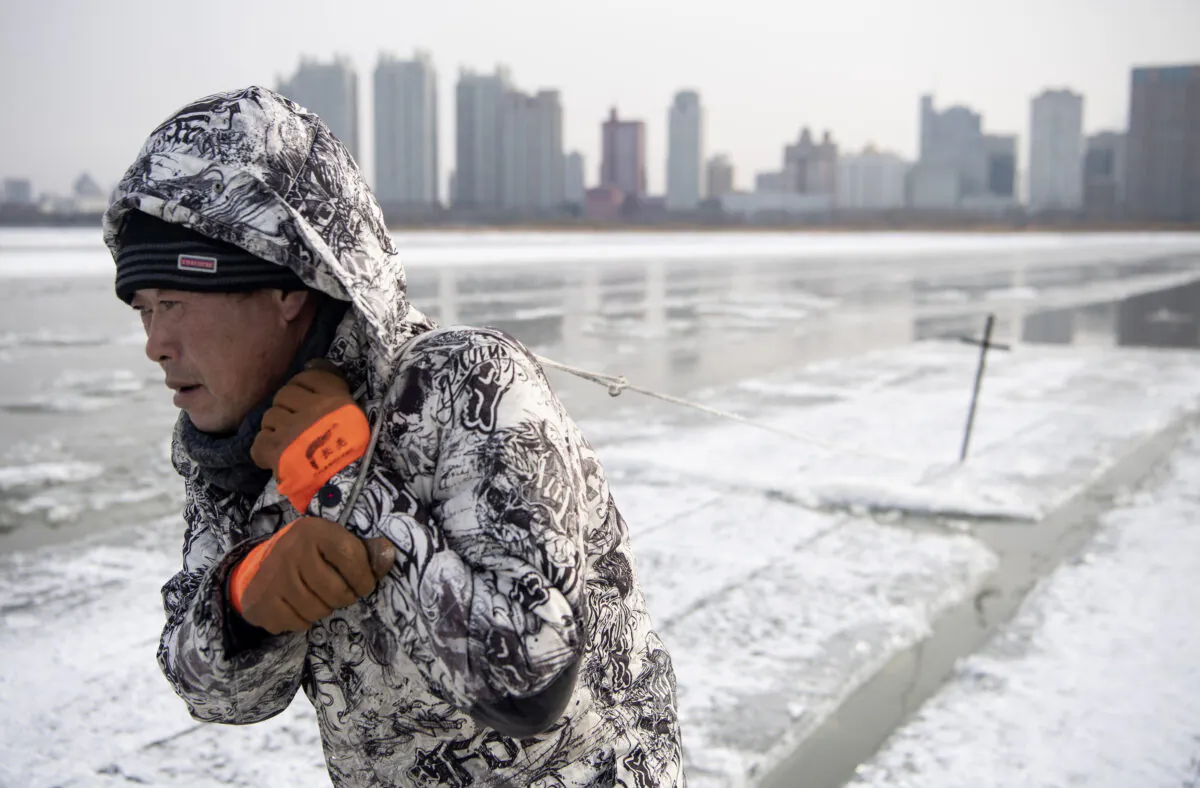 A worker drags ice blocks on the frozen Songhua river in Harbin, China, on Dec. 11, 2019. (Noel Celis/AFP via Getty Images)