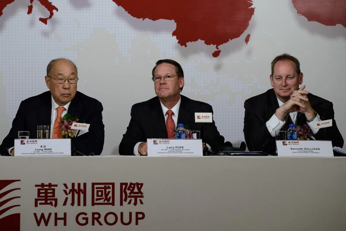 Executive director and chairman of WH Group, Wan Long, Executive director and president of Smithfield, Larry Pope and Smithfield chief financial officer, Kenneth Sullivan attend a press conference in Hong Kong on April 14, 2014. (Philippe Lopez/AFP via Getty Images)
