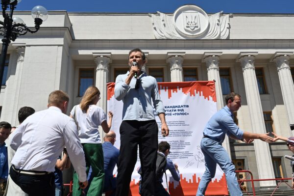 Member of the Ukrainian Parliament, founder of Ukrainian political party 'Golos' (Voice) and rock star Svyatoslav Vakarchuk speaks, as members of his party sign a banner with the headline, "Commitment of deputies candidates of the political party Golos (Voice) to the parliament" during an election campaign rally "Change the Parliament, Change the Country" in front of the parliament's building in Kiev on June 25, 2019. (Sergei Supinsky /AFP via Getty Images)