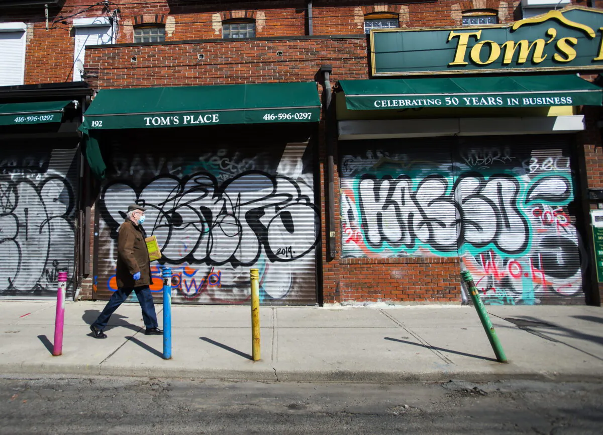 A lone person walks past closed businesses in Kensington Market in Toronto on April 15, 2020. (Nathan Denette/The Canadian Press)