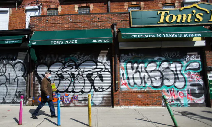 A lone person walks past closed businesses in Kensington Market in Toronto, Canada, on April 15, 2020. (Nathan Denette/The Canadian Press)